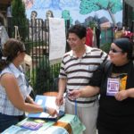 People gathered together receiving flyers at a park for healthy homes.