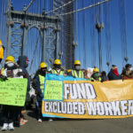 Excluded Workers take on the Manhattan Bridge folding a "Fund Excluded Workers" banner.