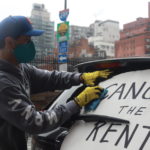 Jose Lopez hangs a banner on his car calling to Cancel Rent.